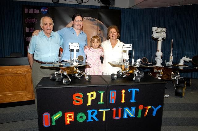 NASA image: KENNEDY SPACE CENTER, FLA. -  Nine-year-old Sofi Collis (third from left) and her family pose proudly with a banner displaying the names she selected for the Mars Exploration Rovers -- "Spirit" and "Opportunity" -- following a press conference announcing the names. The names Sofi suggested were chosen from more than 10,000 student entries in an essay contest managed for NASA by the LEGO Company. NASA's twin Mars Exploration Rovers are designed to study the history of water on Mars. These robotic geologists are equipped with a robotic arm, a drilling tool, three spectrometers, and four pairs of cameras that allow them to have a human-like, 3D view of the terrain. Each rover could travel as far as 100 meters in one day to act as Mars scientists' eyes and hands, exploring an environment where humans are not yet able to go. MER-A, with the rover Spirit aboard, is scheduled to launch on June 8 at 2:06 p.m. EDT, with two launch opportunities each day during a launch period that closes on June 24.