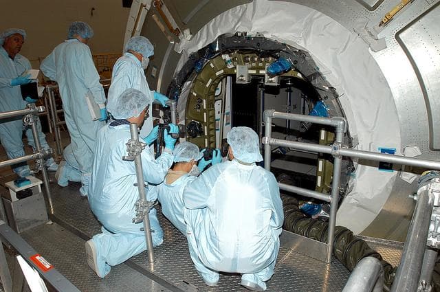 NASA image: KENNEDY SPACE CENTER, FLA. -  Workers in the Space Station Processing Facility attempt to open the hatch on the Italian-built Node 2, a future element of the International Space Station.  Node 2 arrived at KSC June 1.  The second of three Station connecting modules, the module  attaches to the end of the U.S. Lab and provides attach locations for the Japanese laboratory, European laboratory, the Centrifuge Accommodation Module and, later, Multipurpose Logistics Modules. It will provide the primary docking location for the Shuttle when a pressurized mating adapter is attached to Node 2.  Installation of the module will complete  the U.S. Core of the ISS.  Node 2 is the designated payload for mission STS-120.  No orbiter or launch date has been determined yet.Installation of the module will complete  the U.S. Core of the ISS.  Node 2 is the designated payload for mission STS-120.  No orbiter or launch date has been determined yet.