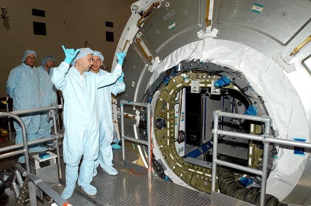 NASA image: KENNEDY SPACE CENTER, FLA. -  In the Space Station Processing Facility, workers talk near the opened hatch of the Italian-built Node 2.  A future element of the International Space Station,  Node 2 arrived at KSC June 1.  The second of three Station connecting modules, Node 2 attaches to the end of the U.S. Lab and provides attach locations for the Japanese laboratory, European laboratory, the Centrifuge Accommodation Module and, later, Multipurpose Logistics Modules. It will provide the primary docking location for the Shuttle when a pressurized mating adapter is attached to Node 2.  Installation of the module will complete  the U.S. Core of the ISS.  Node 2 is the designated payload for mission STS-120.  No orbiter or launch date has been determined yet.