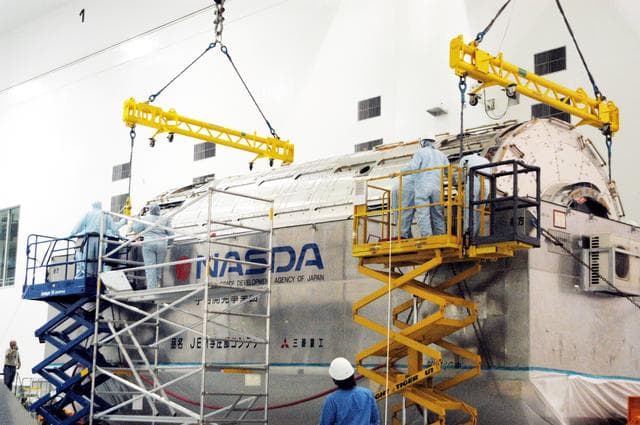 NASA image: KENNEDY SPACE CENTER, FLA. -  Workers in the Space Station Processing Facility attach an overhead crane to the Japanese Experiment Module (JEM) pressure module inside its canister.  The module will be removed and transferred to a work stand in the Space Station Processing Facility.  A research laboratory, the pressurized module is the first element of the JEM, named "Kibo" (Hope), to be delivered to KSC.   The National Space Development Agency of Japan (NASDA) developed the laboratory at the Tsukuba Space Center near Tokyo and is Japan's primary contribution to the Station. It will enhance the unique research capabilities of the orbiting complex by providing an additional environment for astronauts to conduct science experiments.  The JEM also includes an exposed facility (platform) for space environment experiments, a robotic manipulator system, and two logistics modules. The various JEM components will be  assembled in space over the course of three Shuttle missions.