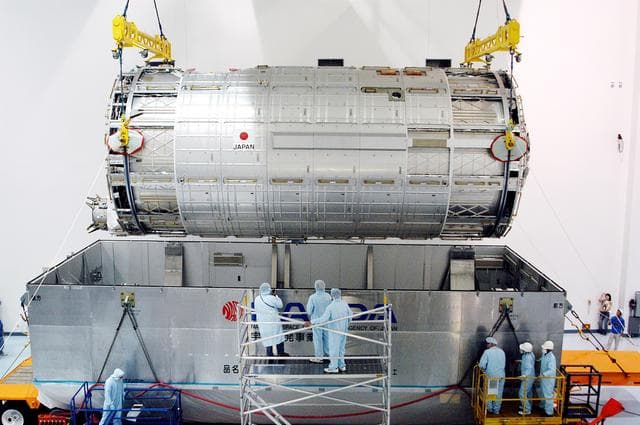 NASA image: KENNEDY SPACE CENTER, FLA. -  In the Space Station Processing Facility, an overhead crane lifts the Japanese Experiment Module (JEM) pressure module out of the shipping canister to move it to a work stand.  A research laboratory, the pressurized module is the first element of the JEM, named "Kibo" (Hope), to be delivered to KSC.   The National Space Development Agency of Japan (NASDA) developed the laboratory at the Tsukuba Space Center near Tokyo and is Japan's primary contribution to the Station. It will enhance the unique research capabilities of the orbiting complex by providing an additional environment for astronauts to conduct science experiments.  The JEM also includes an exposed facility (platform) for space environment experiments, a robotic manipulator system, and two logistics modules. The various JEM components will be  assembled in space over the course of three Shuttle missions.