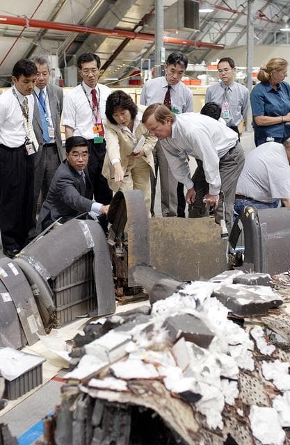 NASA image: KENNEDY SPACE CENTER, FLA. -  On a KSC visit, Executive Director of NASDA Koji Yamamoto (kneeling, left) reaches out to a piece of Columbia debris in the Columbia Debris Hangar.  At right is Shuttle Launch Director Mike Leinbach, who is explaining recovery and reconstruction efforts.  Mr. Yamamoto is at KSC for a welcome ceremony involving the arrival of the newest Space Station module, the Japanese Experiment Module/pressurized module.