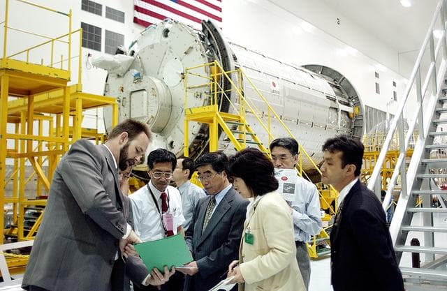 NASA image: KENNEDY SPACE CENTER, FLA. -  In the Space Station Processing Facility, Executive Director of NASDA Koji Yamamoto (center) gets information about the facility while on a tour of KSC.  Behind the group is the Japanese Experiment Module (JEM)/pressurized module.  Mr. Yamamoto is at KSC for a welcome ceremony involving the arrival of JEM.