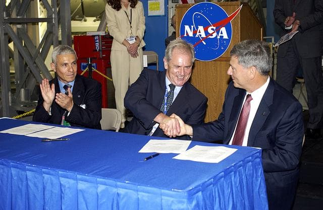 NASA image: KENNEDY SPACE CENTER, FLA. - At a ceremony highlighting the arrival of two major components of the International Space Station, Node 2 and the Japanese Experiment Module (JEM), ownership of Node 2 was officially transferred between the European Space Agency (ESA) and NASA.  Shaking hands after the signing are Alan Thirkettle (center), International Space Station Program manager for Node 2, ESA; and NASA’s Michael C. Kostelnik (right), deputy associate administrator for International Space Station and Shuttle Programs.  At left, also part of the signing, is Andrea Lorenzoni (left), International Space Station Program manager for Node 2, Italian Space Agency.  NASA's Node 2, built by ESA in Italy, arrived at KSC on June 1. It will be the next pressurized module installed on the Station. The pressurized module of the Japanese Experiment Module (JEM),  named "Kibo" (Hope), arrived at KSC on June 4. It is Japan's primary contribution to the Station. Emceed by Lisa Malone, deputy director of External Relations and Business Development at KSC, the ceremony also included these speakers: Center Director Roy Bridges Jr.; NASA’s William Gerstenmaier, International Space Station Program manager; and Kuniaki Shiraki, JEM Project manager, National Aerospace and Development Agency of Japan.