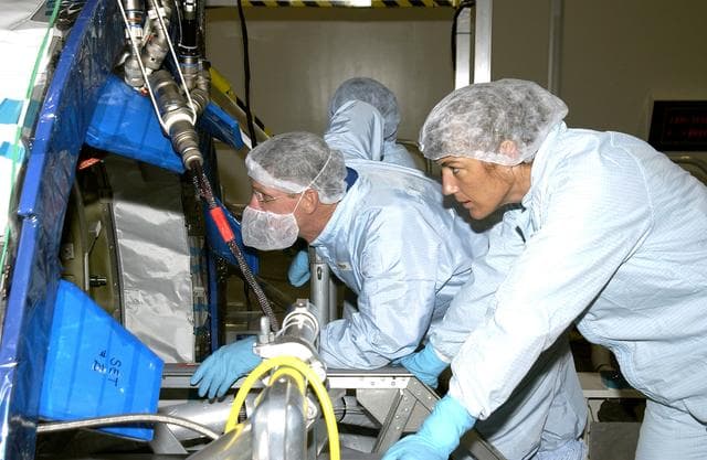 NASA image: KENNEDY SPACE CENTER, FLA. -  In the Space Station Processing Facility, STS-115 Mission Specialists Joseph Tanner (left) and Heidemarie Stefanyshyn-Piper (right)  look over the Japanese Experiment Module (JEM) Pressurized Module located in the Space Station Processing Facility. Known as Kibo, the JEM consists of six components: two research facilities -- the Pressurized Module and Exposed Facility; a Logistics Module attached to each of them; a Remote Manipulator System; and an Inter-Orbit Communication System unit. Kibo also has a scientific airlock through which experiments are transferred and exposed to the external environment of space. The various components of JEM will be assembled in space over the course of three Space Shuttle missions.  The STS-115  mission will deliver the second port truss segment, the P3/P4 Truss, to attach to the first port truss segment, the P1 Truss, as well as deploy solar array sets 2A and 4A..  The crew is scheduled to activate and check out the Solar Alpha Rotary Joint (SARJ) and deploy the P4 Truss radiator.