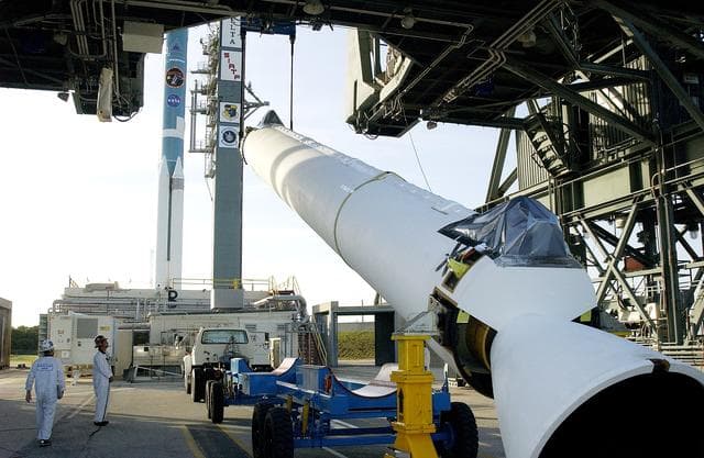 KENNEDY SPACE CENTER, FLA. -   A solid rocket booster (SRB) for the Delta II Heavy rocket that will launch the Space Infrared Telescope Facility (SIRTF) is lifted off its transporter on Launch Complex 17-B, Cape Canaveral Air Force Station.  The SRB will be added to the launch vehicle in the background.  The Delta II Heavy features nine 46-inch-diameter, stretched SRBs.  SIRTF, consisting of three cryogenically cooled science instruments and an 0.85-meter telescope, is one of NASA's largest infrared telescopes to be launched.  SIRTF will obtain images and spectra by detecting the infrared energy, or heat, radiated by objects in space. Most of this infrared radiation is blocked by the Earth's atmosphere and cannot be observed from the ground.