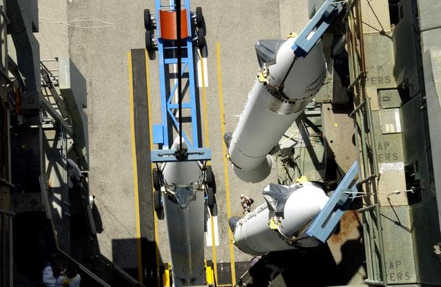 NASA image: KENNEDY SPACE CENTER, FLA. -   This view from the mobile service tower on Launch Complex 17-B, Cape Canaveral Air Force Station, shows two solid rocket boosters (SRBs) already suspended in the tower while another is being lifted.  They are three of nine  46-inch-diameter, stretched SRBs that are being attached to the Delta II Heavy rocket that will launch the Space Infrared Telescope Facility (SIRTF).  Consisting of three cryogenically cooled science instruments and an 0.85-meter telescope, SIRTF is one of NASA's largest infrared telescopes to be launched.  SIRTF will obtain images and spectra by detecting the infrared energy, or heat, radiated by objects in space. Most of this infrared radiation is blocked by the Earth's atmosphere and cannot be observed from the ground.