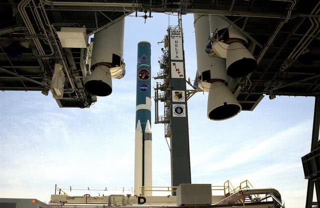 KENNEDY SPACE CENTER, FLA. -   On Launch Complex 17-B, Cape Canaveral Air Force Station, the Delta II Heavy rocket  (background) is framed by the solid rocket boosters (foreground) suspended in the mobile service tower.  The SRBs will be added to those already attached to the rocket.  The Delta II Heavy will launch the Space Infrared Telescope Facility (SIRTF).  Consisting of three cryogenically cooled science instruments and an 0.85-meter telescope, SIRTF is one of NASA's largest infrared telescopes to be launched.  SIRTF will obtain images and spectra by detecting the infrared energy, or heat, radiated by objects in space. Most of this infrared radiation is blocked by the Earth's atmosphere and cannot be observed from the ground.