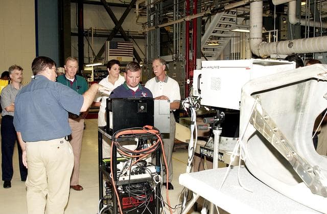 NASA image: KENNEDY SPACE CENTER, FLA.  -  Members of the  Stafford-Covey Return to Flight Task Group (SCTG) look over equipment in the Orbiter Processing Facility.  At left (back to camera), Fernando Santos, with NASA, and Paul Ogletree (at monitor), with United Space Alliance, describe how flash thermography is used to inspect the structure of Reinforced Carbon Carbon panels and establish a baseline on panels before flight.  Chairing the task group are Richard O. Covey (far right), former Space Shuttle commander, and Thomas P. Stafford, Apollo commander.  Chartered by NASA Administrator Sean O’Keefe, the task group will perform an independent assessment of NASA’s implementation of the final recommendations by the Columbia Accident Investigation Board.