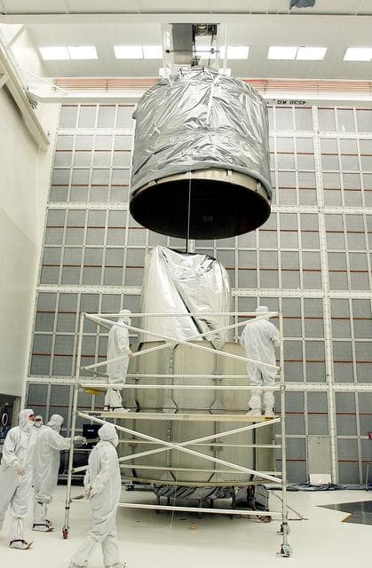 NASA image: KENNEDY SPACE CENTER, FLA.  -  In Hangar A&E, Cape Canaveral Air Force Station, the upper canister is lowered toward the Space Infrared Telescope Facility (SIRTF) below.  After encapsulation is complete, the spacecraft will be transported to Launch Complex 17-B for mating with its launch vehicle, the Delta II rocket.   SIRTF consists of three cryogenically cooled science instruments and an 0.85-meter telescope, and is one of NASA's largest infrared telescopes to be launched.  SIRTF will obtain images and spectra by detecting the infrared energy, or heat, radiated by objects in space. Most of this infrared radiation is blocked by the Earth's atmosphere and cannot be observed from the ground.