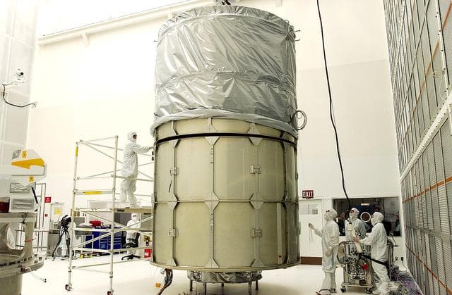 NASA image: KENNEDY SPACE CENTER, FLA.  -  In Hangar A&E, Cape Canaveral Air Force Station, the upper canister is mated to the middle panels around the Space Infrared Telescope Facility (SIRTF).  The spacecraft will be transported to Launch Complex 17-B for mating with its launch vehicle, the Delta II rocket.   SIRTF consists of three cryogenically cooled science instruments and an 0.85-meter telescope, and is one of NASA's largest infrared telescopes to be launched.  SIRTF will obtain images and spectra by detecting the infrared energy, or heat, radiated by objects in space. Most of this infrared radiation is blocked by the Earth's atmosphere and cannot be observed from the ground.