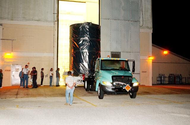 NASA image: KENNEDY SPACE CENTER, FLA.  -  The Space Infrared Telescope Facility (SIRTF) is rolled out of the hangar at Cape Canaveral Air Force Station during pre-dawn hours.  It is being transported to Launch Pad 17-B where it will be lifted into the mobile service tower and prepared for launch.  SIRTF consists of three cryogenically cooled science instruments and an 0.85-meter telescope, and is one of NASA’s largest infrared telescopes to be launched.  It is the fourth and final element in NASA’s family of orbiting “Great Observatories.”  SIRTF will obtain images and spectra by detecting the infrared energy, or heat, radiated by objects in space. Most of this infrared radiation is blocked by the Earth's atmosphere and cannot be observed from the ground.