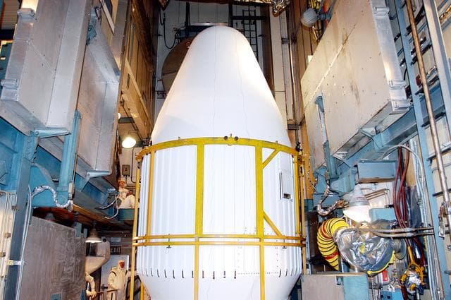 NASA image: KENNEDY SPACE CENTER, FLA.  - In the mobile service tower on Launch Pad 17-B, Cape Canaveral Air Force Station, the top of the fairing is seen as it moves into place around the Space Infrared Telescope Facility (SIRTF). SIRTF will obtain images and spectra by detecting the infrared energy, or heat, radiated by objects in space. Consisting of a 0.85-meter telescope and three cryogenically cooled science instruments, SIRTF will be the largest infrared telescope ever launched into space. It is the fourth and final element in NASA’s family of orbiting “Great Observatories.” Its highly sensitive instruments will give a unique view of the Universe and peer into regions of space that are hidden from optical telescopes.