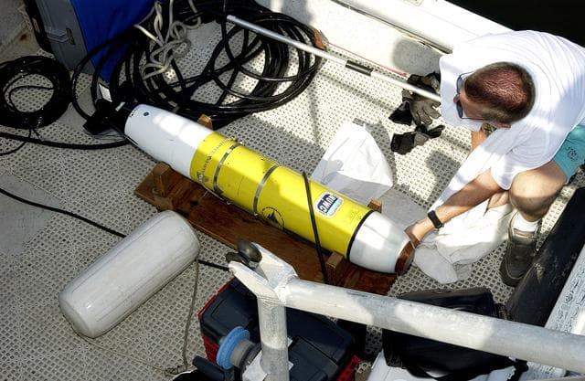 NASA image: KENNEDY SPACE CENTER, FLA.  -  A research team member aboard one of the watercraft being utilized to conduct underwater acoustic research in the Launch Complex 39 turn basin prepares some of the project's equipment for placement in the water.  Several government agencies, including NASA, NOAA, the Navy, the Coast Guard, and the Florida Fish and Wildlife Commission are involved in the testing. The research involves demonstrations of passive and active sensor technologies, with applications in fields ranging from marine biological research to homeland security. The work is also serving as a pilot project to assess the cooperation between the agencies involved. Equipment under development includes a passive acoustic monitor developed by NASA’s Jet Propulsion Laboratory, and mobile robotic sensors from the Navy’s Mobile Diving and Salvage Unit.