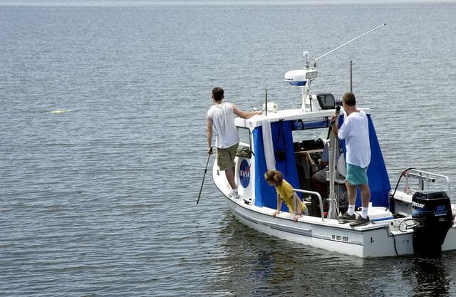 NASA image: KENNEDY SPACE CENTER, FLA.  -  Research team members aboard one of the watercraft being utilized to conduct underwater acoustic research in the Launch Complex 39 turn basin monitor some of the project's equipment just released into the water.  Several government agencies, including NASA, NOAA, the Navy, the Coast Guard, and the Florida Fish and Wildlife Commission are involved in the testing. The research involves demonstrations of passive and active sensor technologies, with applications in fields ranging from marine biological research to homeland security. The work is also serving as a pilot project to assess the cooperation between the agencies involved. Equipment under development includes a passive acoustic monitor developed by NASA’s Jet Propulsion Laboratory, and mobile robotic sensors from the Navy’s Mobile Diving and Salvage Unit.