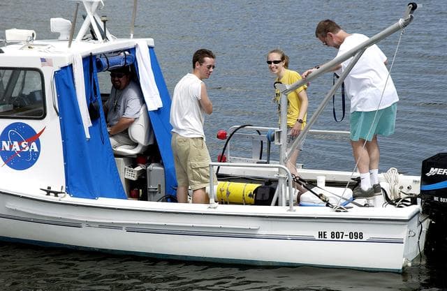 NASA image: KENNEDY SPACE CENTER, FLA.  -  Research team members aboard one of the watercraft being utilized to conduct underwater acoustic research in the Launch Complex 39 turn basin secure some of the project's equipment back into the vessel.  Several government agencies, including NASA, NOAA, the Navy, the Coast Guard, and the Florida Fish and Wildlife Commission are involved in the testing. The research involves demonstrations of passive and active sensor technologies, with applications in fields ranging from marine biological research to homeland security. The work is also serving as a pilot project to assess the cooperation between the agencies involved. Equipment under development includes a passive acoustic monitor developed by NASA’s Jet Propulsion Laboratory, and mobile robotic sensors from the Navy’s Mobile Diving and Salvage Unit.