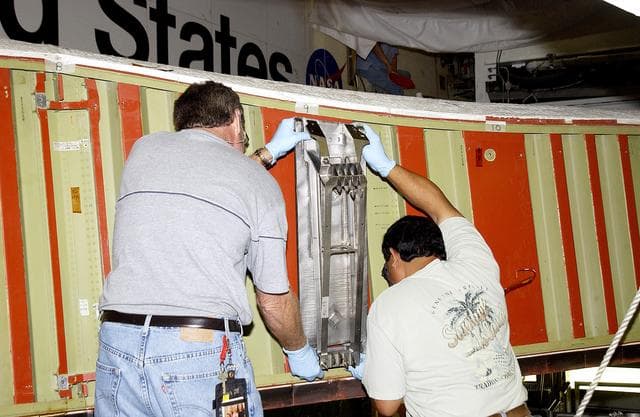NASA image: KENNEDY SPACE CENTER, FLA. -  Mike Hyatt (left) and Saul Ngy, technicians with United Space Alliance, install a spar on the wing of the orbiter Atlantis.  The Reinforced Carbon Carbon (RCC) panels are mechanically attached to the wing with a series of floating joints - spars - to reduce loading on the panels caused by wing deflections. The aluminum and the metallic attachments are protected from exceeding temperature limits by internal insulation.
