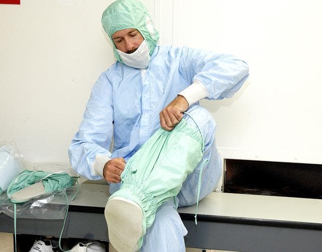 NASA image: KENNEDY SPACE CENTER, FLA. -  A KSC employee dons the foot and leg covers of a "bunny suit," part of standard clean room apparel, before entering a clean room. The apparel is designed to cover the hair, clothing and shoes of employees to prevent particulate matter from contaminating the space flight hardware being stored or processed in the clean room and is one aspect of KSC's Foreign Object Debris (FOD) control program, an important safety initiative.