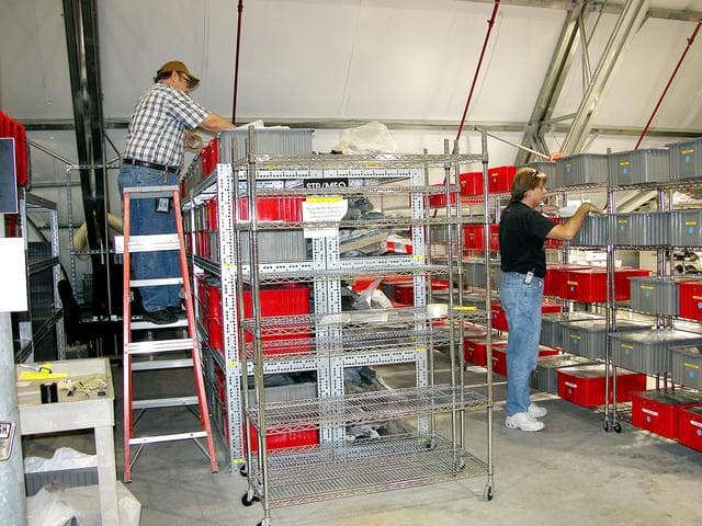 NASA image: KENNEDY SPACE CENTER, FLA.  - Workers in the Columbia Debris Hangar  pull items from storage containers to transfer  to storage in the Vehicle Assembly Building.   About 83,000 pieces were shipped to KSC during search and recovery efforts in East Texas.