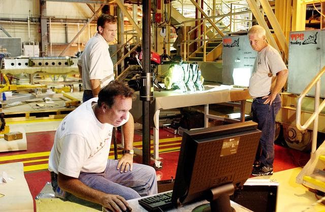 NASA image: KENNEDY SPACE CENTER, FLA. -  John Macke (standing, left), with Boeing St. Louis, Alden Pitard (seated, left) and Dan Clark (right), with KSC Boeing, look at a monitor after 3D digital scanning of actuators in the Orbiter Processing Facility.  There are two actuators per engine on the Shuttle, one for pitch motion and one for yaw motion. The Space Shuttle Main Engine hydraulic servoactuators are used to gimbal the main engine.