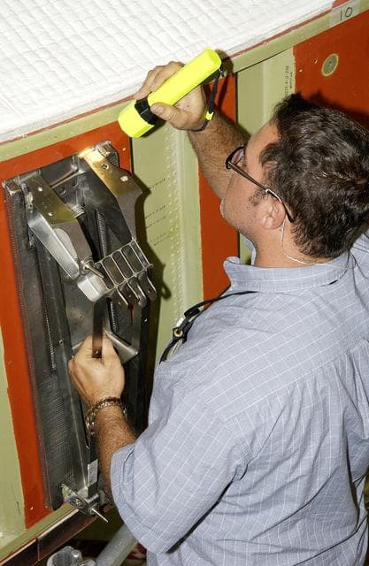 NASA image: KENNEDY SPACE CENTER, FLA. - In the Orbiter Processing Facility, John Newport, with United Space Alliance, inspects spar installation on the wing of the orbiter Atlantis.  Reinforced Carbon Carbon (RCC) panels are mechanically attached to the wing with a series of floating joints - spars - to reduce loading on the panels caused by wing deflections. The aluminum and the metallic attachments are protected from exceeding temperature limits by internal insulation.