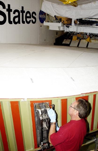 NASA image: KENNEDY SPACE CENTER, FLA. -  In the Orbiter Processing Facility, Mike Hyatt, with United Space Alliance, installs a spar on the wing of the orbiter Atlantis.  Reinforced Carbon Carbon (RCC) panels are mechanically attached to the wing with a series of floating joints - spars - to reduce loading on the panels caused by wing deflections. The aluminum and the metallic attachments are protected from exceeding temperature limits by internal insulation.