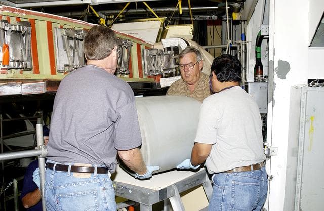 NASA image: KENNEDY SPACE CENTER, FLA. - In the Orbiter Processing Facility, United Space Alliance workers Mike Hyatt (left) Jerry Belt (center), and Saul Ngy (right), lift a Reinforced Carbon Carbon (RCC) panel they will attach to the leading edge of the wing of the orbiter Atlantis.  The gray carbon composite RCC panels have sufficient strength to withstand the aerodynamic forces experienced during launch and reentry, which can reach as high as 800 pounds per square foot.  The operating range of RCC is from minus 250º F to about 3,000º F, the temperature produced by friction with the atmosphere during reentry.
