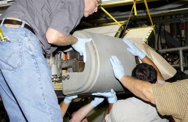 NASA image: KENNEDY SPACE CENTER, FLA. - In the Orbiter Processing Facility, United Space Alliance workers Mike Hyatt (left) Saul Ngy (center) and Jerry Belt (right) lift a Reinforced Carbon Carbon (RCC) panel to attach onto the leading edge of the wing of the orbiter Atlantis.  The gray carbon composite RCC panels have sufficient strength to withstand the aerodynamic forces experienced during launch and reentry, which can reach as high as 800 pounds per square foot.  The operating range of RCC is from minus 250º F to about 3,000º F, the temperature produced by friction with the atmosphere during reentry.