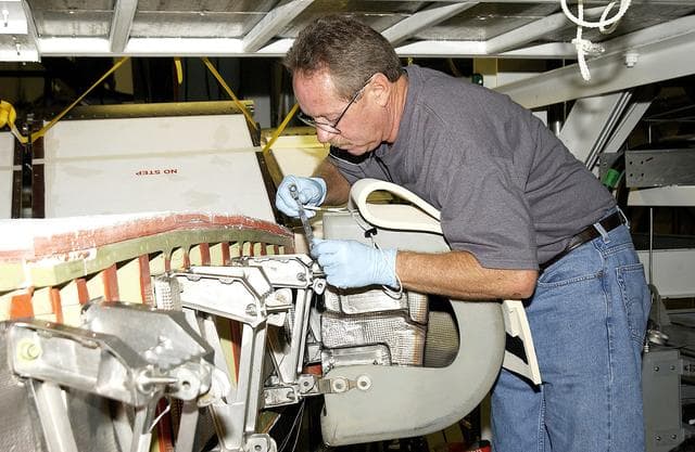 NASA image: KENNEDY SPACE CENTER, FLA. -  In the Orbiter Processing Facility, United Space Alliance worker Mike Hyatt attaches a Reinforced Carbon Carbon (RCC) panel onto the leading edge of the wing of the orbiter Atlantis.  The gray carbon composite RCC panels have sufficient strength to withstand the aerodynamic forces experienced during launch and reentry, which can reach as high as 800 pounds per square foot. The operating range of RCC is from minus 250º F to about 3,000º F, the temperature produced by friction with the atmosphere during reentry.