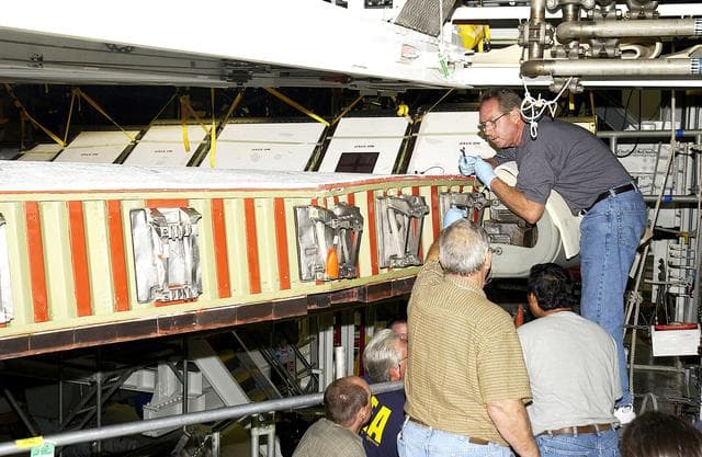 NASA image: KENNEDY SPACE CENTER, FLA. -  In the Orbiter Processing Facility, United Space Alliance worker Mike Hyatt (above) attaches a Reinforced Carbon Carbon (RCC) panel onto the leading edge of the wing of the orbiter Atlantis.  The gray carbon composite RCC panels have sufficient strength to withstand the aerodynamic forces experienced during launch and reentry, which can reach as high as 800 pounds per square foot.  The operating range of RCC is from minus 250º F to about 3,000º F, the temperature produced by friction with the atmosphere during reentry.
