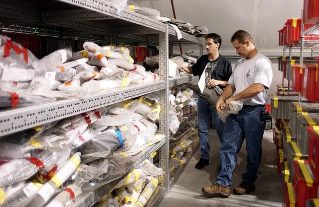 NASA image: KENNEDY SPACE CENTER, FLA. - In the Columbia Debris Hangar,  Jim Delie (left) and Don Eitel select from the shelves wrapped pieces of debris to be packed into storage boxes.  About 83,000 pieces of debris were shipped to KSC during search and recovery efforts in East Texas. That represents about 38 percent of the dry weight of Columbia, equaling almost 85,000 pounds.  An area of the Vehicle Assembly Building is being prepared to store the debris.