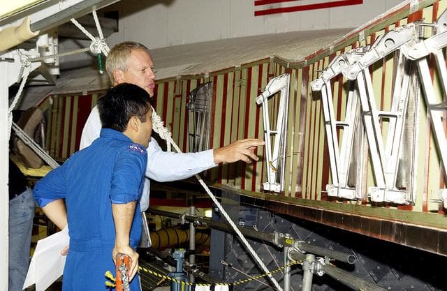 NASA image: KENNEDY SPACE CENTER, FLA. -  William Gaetjens (background), with the Vehicle Integration Test Team (VITT) directs Japanese astronaut Koichi Wakata’s attention to the spars installed on the wing of the orbiter Atlantis.  Reinforced Carbon Carbon (RCC) panels are mechanically attached to the wing via the spars - a series of floating joints - to reduce loading on the panels caused by wing deflections. The aluminum and the metallic attachments are protected from exceeding temperature limits by internal insulation.