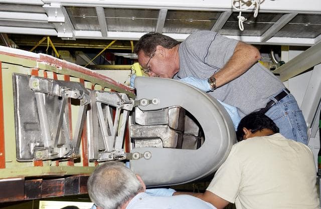 NASA image: KENNEDY SPACE CENTER, FLA. -  In the Orbiter Processing Facility, United Space Alliance workers  Mike Hyatt (above),  Saul Ngy (right) and Jerry Belt (below) install a Reinforced Carbon Carbon (RCC) panel to the leading edge of the wing of the orbiter Atlantis.  The gray carbon composite RCC panels have sufficient strength to withstand the aerodynamic forces experienced during launch and reentry, which can reach as high as 800 pounds per square foot.  The operating range of RCC is from minus 250º F to about 3,000º F, the temperature produced by friction with the atmosphere during reentry.