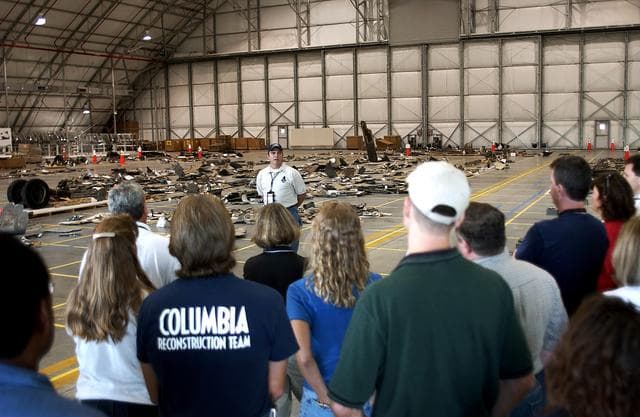 NASA image: KENNEDY SPACE CENTER, FLA. -  Jim Comer, United Space Alliance project leader for Columbia reconstruction, speaks to members of the Columbia Reconstruction Team during transfer of debris from the Columbia Debris Hangar to its permanent storage site in the Vehicle Assembly Building.  More than 83,000 pieces of debris were shipped to KSC during search and recovery efforts in East Texas. That represents about 38 percent of the dry weight of Columbia, equaling almost 85,000 pounds.