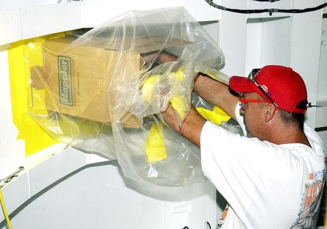 NASA image: KENNEDY SPACE CENTER, FLA. - In the Solid Rocket Booster Assembly and Refurbishment Facility (ARF), Troy Krout, with United Space Alliance, works on positioning the parachute camera after installation on the solid rocket booster forward skirt.  Refurbishment and subassembly of Shuttle SRB hardware - primarily the forward and aft assemblies - is carried out in the ARF.
