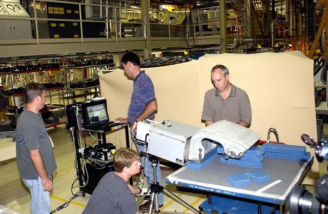 NASA image: KENNEDY SPACE CENTER, FLA. - In the Orbiter Processing Facility, United Space Alliance workers share the task of examining  a Reinforced Carbon Carbon panel using flash thermography.  From left are Paul Ogletree, Jim Landy (kneeling), Dan Phillips and Dan Kenna.  Attached to the leading edge of the wing of the orbiters,  the gray carbon composite RCC panels have sufficient strength to withstand the aerodynamic forces experienced during launch and reentry, which can reach as high as 800 pounds per square foot.  The operating range of RCC is from minus 250º F to about 3,000º F, the temperature produced by friction with the atmosphere during reentry.