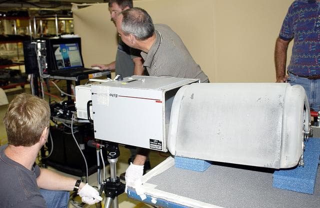 NASA image: KENNEDY SPACE CENTER, FLA. - In the Orbiter Processing Facility, United Space Alliance workers (left to right) Jim Landy, Paul Ogletree, Dan Kenna and Dan Phillips check results of flash thermography on the Reinforced Carbon Carbon panel on the table (foreground).  Attached to the leading edge of the wing of the orbiters,  the gray carbon composite RCC panels have sufficient strength to withstand the aerodynamic forces experienced during launch and reentry, which can reach as high as 800 pounds per square foot.  The operating range of RCC is from minus 250º F to about 3,000º F, the temperature produced by friction with the atmosphere during reentry.