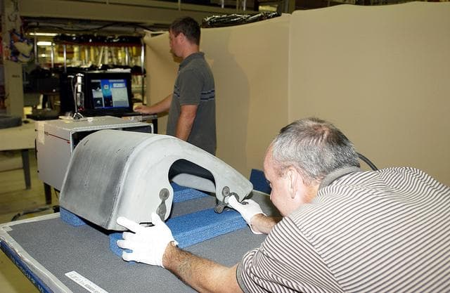 NASA image: KENNEDY SPACE CENTER, FLA. -  In the Orbiter Processing Facility, United Space Alliance worker Dan Kenna (right) positions a Reinforced Carbon Carbon panel on the table to perform flash thermography.  In the background, Paul Ogletree observes the monitor.  Attached to the leading edge of the wing of the orbiters,  the gray carbon composite RCC panels have sufficient strength to withstand the aerodynamic forces experienced during launch and reentry, which can reach as high as 800 pounds per square foot.  The operating range of RCC is from minus 250º F to about 3,000º F, the temperature produced by friction with the atmosphere during reentry.