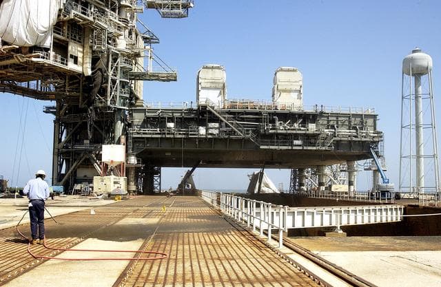 NASA image: KENNEDY SPACE CENTER, FLA. - A worker sandblasts the surface behind the Mobile Launcher Platform on Launch Pad 39A .  Routine maintenance includes sandblasting and repainting as preventive means to minimize corrosion.