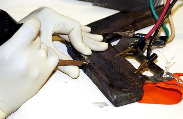 NASA image: KENNEDY SPACE CENTER, FLA. -  United Space Alliance employee Anthony Simmons electrowelds a crack formed in the insulator inside a Reinforced Carbon Carbon panel.   The gray carbon composite RCC panels are attached to the leading edge of the wing of the orbiters to withstand the aerodynamic forces experienced during launch and reentry, which can reach as high as 800 pounds per square foot.  The operating range of RCC is from minus 250º F to about 3,000º F, the temperature produced by friction with the atmosphere during reentry.