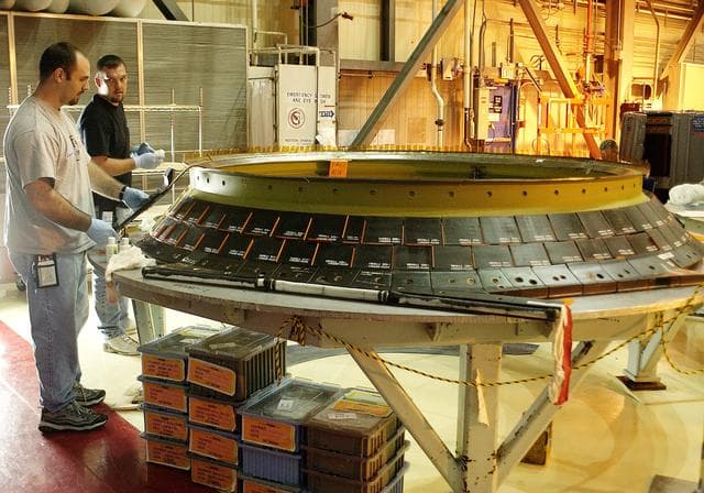 NASA image: KENNEDY SPACE CENTER, FLA. -  United Space Alliance employees Jeremy Schwarz (left) and Chris Keeling install new tiles on the heat shield of main engine 1 for the orbiter Discovery.  A heat shield is a protective layer on a spacecraft designed to protect it from the high temperatures, usually those that result from aerobraking during reentry into the Earth’s atmosphere.