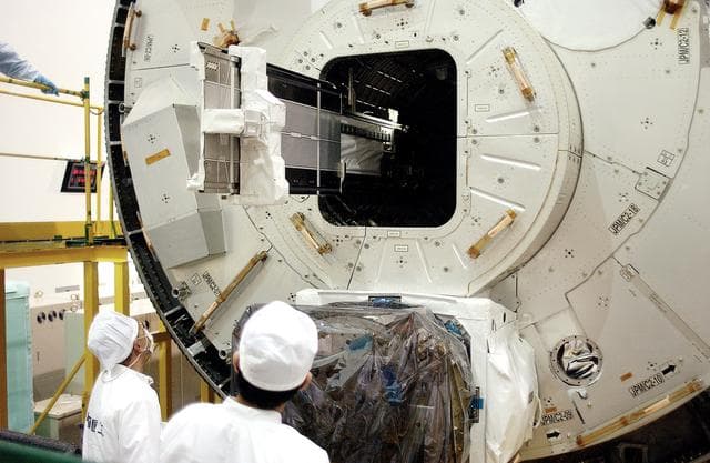 NASA image: KENNEDY SPACE CENTER, FLA. - In the Space Station Processing Facility, technicians on the floor watch as a tray is extended from inside the Pressurized Module, or PM, part of the Japanese Experiment Module (JEM).   The PM provides a shirt-sleeve environment in which astronauts on the International Space Station can conduct microgravity experiments. There are a total of 23 racks, including 10 experiment racks, inside the PM providing a power supply, communications, air conditioning, hardware cooling, water control and experiment support functions.