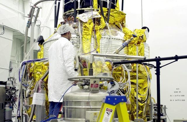 NASA image: VANDENBERG AFB, CALIF. -   A worker in the spacecraft processing facility on North Vandenberg Air Force Base checks the Gravity Probe B experiment during prelaunch testing.  The Gravity Probe B will launch a payload of four gyroscopes into low-Earth polar orbit to test two extraordinary predictions of Albert Einstein’s general theory of relativity: the geodetic effect (how space and time are warped by the presence of the Earth) and frame dragging (how Earth’s rotation drags space and time around with it). Once in orbit, for 18 months each gyroscope’s spin axis will be monitored as it travels through local spacetime, observing and measuring these effects.  The experiment was developed by Stanford University, Lockheed Martin and NASA’s Marshall Space Flight Center.   The targeted launch date is Dec. 6, 2003.