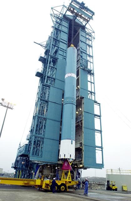 NASA image: VANDENBERG AFB, CALIF. -  The first stage of the Delta II launch vehicle for the Gravity Probe B experiment is ready to be lifted up the mobile service tower on Space Launch Complex 2, Vandenberg Air Force Base, Calif.  The Gravity Probe B will launch a payload of four gyroscopes into low-Earth polar orbit to test two extraordinary predictions of Albert Einstein’s general theory of relativity: the geodetic effect (how space and time are warped by the presence of the Earth) and frame dragging (how Earth’s rotation drags space and time around with it). Once in orbit, for 18 months each gyroscope’s spin axis will be monitored as it travels through local spacetime, observing and measuring these effects.  The experiment was developed by Stanford University, Lockheed Martin and NASA’s Marshall Space Flight Center.  The targeted launch date is Dec. 6, 2003.