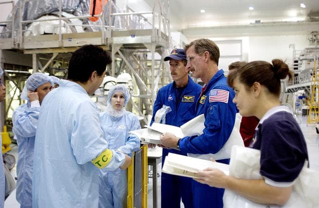 NASA image: KENNEDY SPACE CENTER, FLA. - In the Space Station Processing Facility, workers (in protective clothing) brief STS-117 Mission Specialist James Reilly (center) and STS-115 Mission Specialist Joseph Tanner (right) about the Japanese Experiment Module (JEM).  Equipment familiarization is a routine part of astronaut training and launch preparations.