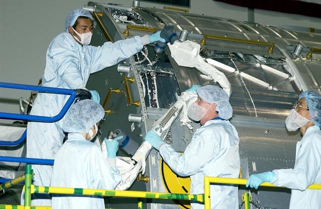 NASA image: KENNEDY SPACE CENTER, FLA. -  In the Space Station Processing Facility, STS-115 Mission Specialist Joseph Tanner (center, foreground) works with technicians to learn more about the Japanese Experiment Module (JEM), known as Kibo.  The JEM consists of six components: two research facilities - the Pressurized Module and the Exposed Facility; a Logistics Module attached to each of them; a Remote Manipulator System; and an Inter-Orbit Communication System unit. Kibo also has a scientific airlock through which experiments are transferred and exposed to the external environment of space. The various components of JEM will be assembled in space over the course of three Space Shuttle missions. Equipment familiarization is a routine part of astronaut training and launch preparations.