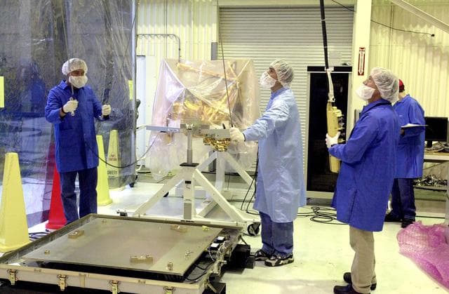 NASA image: VANDENBERG AIR FORCE BASE, CALIF.  -  Outside the clean room at Vandenberg Air Force Base, Calif., the SciSat-1 spacecraft (background) has been removed from the shipping container mounting base (lower left) and placed on the handling fixture. Sci-Sat, which will undergo instrument checkout and spacecraft functional testing, weighs approximately 330 pounds and after launch will be placed in a 400-mile-high polar orbit to investigate processes that control the distribution of ozone in the upper atmosphere. The data from the satellite will provide Canadian and international scientists with improved measurements relating to global ozone processes and help policymakers assess existing environmental policy and develop protective measures for improving the health of our atmosphere, preventing further ozone depletion. The mission is designed to last two years.