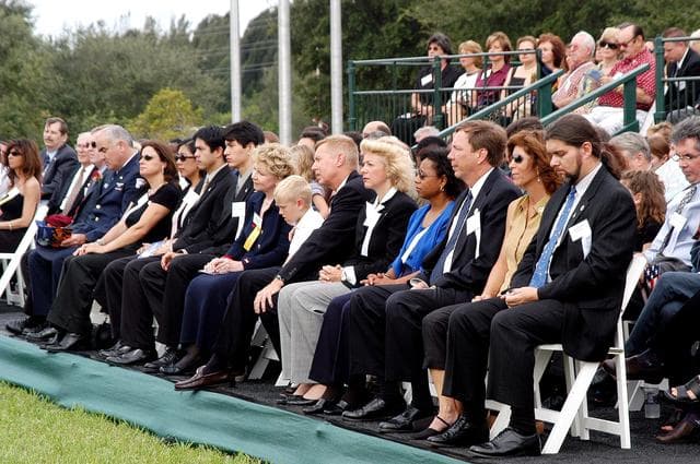 NASA image: KENNEDY SPACE CENTER, FLA. -  Family members of the STS-107 astronauts and other dignitaries attend a dedication ceremony at the Space Mirror Memorial at the Kennedy Space Center Visitor Complex.  During this solemn event, the names of the STS-107 astronauts who lost their lives during the Columbia accident -- Rick Husband, Willie McCool, Laurel Clark, Michael Anderson, David Brown, Kalpana Chawla, and Ilan Ramon -- join the names of 17 other space heroes who gave their lives for the U.S. space program. The "Space Mirror," 42 1/2 feet high by 50 feet wide, illuminates the names of the fallen astronauts cut through the monument's black granite surface.