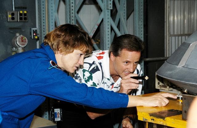NASA image: KENNEDY SPACE CENTER, FLA. -  In the Orbiter Processing Facility, STS-114 Commander Eileen Collins examines part of the Atlantis nose cap with Randall Carter, who is with The  Boeing Company.  The nose cap was  recently removed from Atlantis.  The STS-114 crew is at KSC to take part in crew equipment and orbiter familiarization.