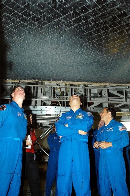 NASA image: KENNEDY SPACE CENTER, FLA. -  In the Orbiter Processing Facility, STS-114 crew members look at the tiles underneath Atlantis.  From left are Mission Specialists Stephen Robinson, Soichi Noguchi and Charles Camarada, who is a new addition to the crew.  Noguchi is with the Japan Aerospace Exploration Agency, JAXA.  The STS-114 crew is at KSC to take part in crew equipment and orbiter familiarization.